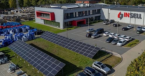 Siedziba firmy Insell widziana z lotu ptaka – budynek z logo Insell, parking i instalacja fotowoltaiczna na trawniku.