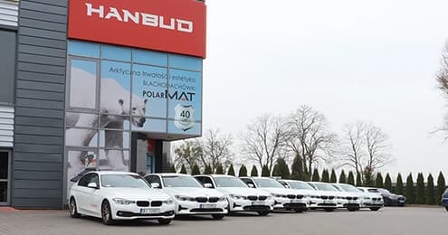 Flota białych samochodów BMW zaparkowanych przed siedzibą firmy Hanbud.