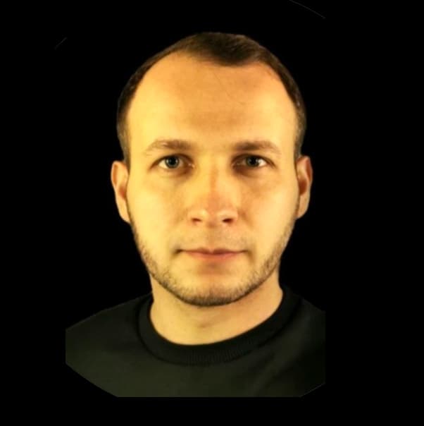Szymon Kustra – portret mężczyzny w czarnej koszulce na ciemnym tle.