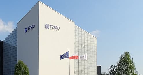 Budynek siedziby TZMO z logo firmy i flagami przed fasadą